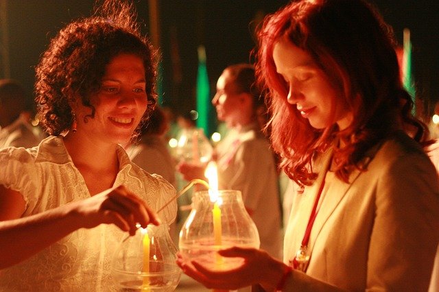 Jovens Mulheres segurando velas acesas, simbolizando fé