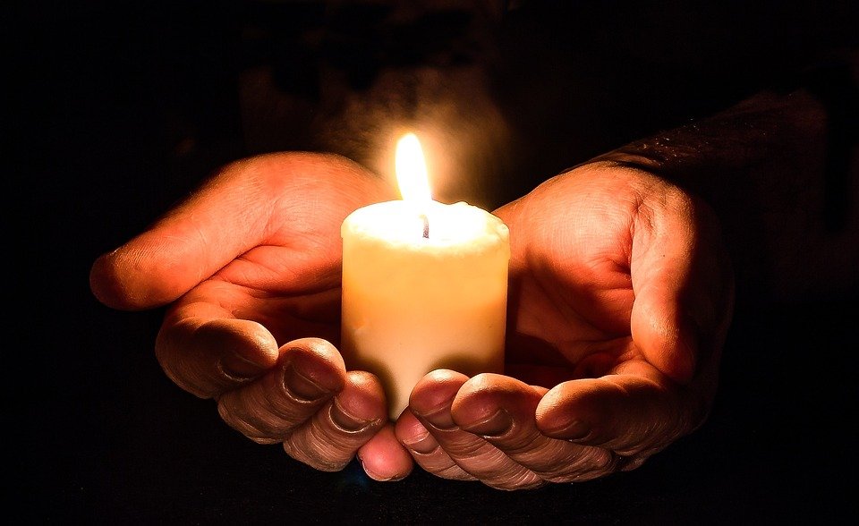 Mãos segurando vela acesa lembrando fé em Deus